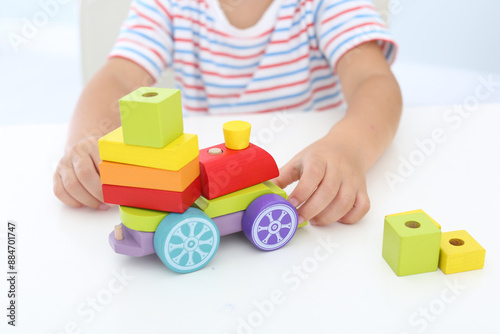 Little boy playing with toy at white table, closeup