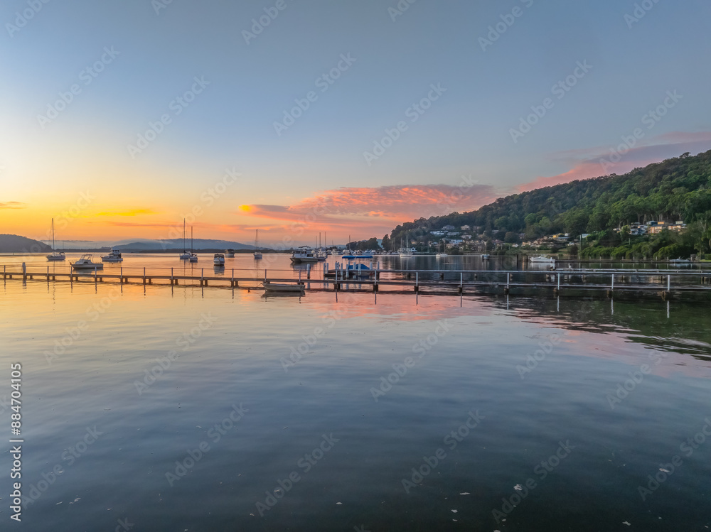Obraz premium Sunrise over the calm water with boats and reflections