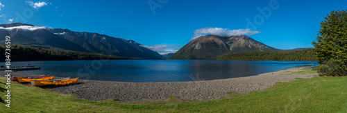 Wide panorama with canoes pulled up on the shore of Lake Rotoiti in Nelson Lakes National Park, New Zealand. Lake and mountains in the background.