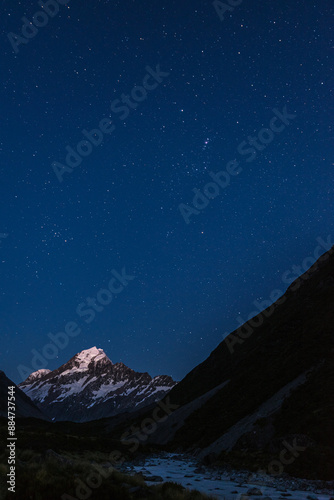 Mount Cook viewed from Hooker valley at night under a clear starlit night, with the constellation Orion prominent. Mt Cook Aoraki National Park, New Zealand.