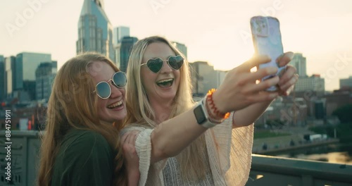Two young female tourists smile and take selfies in downtown Nashville