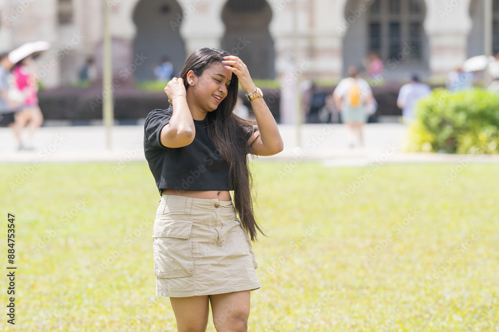 A thirty-something Indian Malaysian mother wearing a miniskirt standing on the expansive lawn at Merdeka Square in Kuala Lumpur, Malaysia. A thirty-something Indian Malaysian mother wearing a miniskirt standing on the expansive lawn at Merdeka Square in Kuala Lumpur, Malaysia.