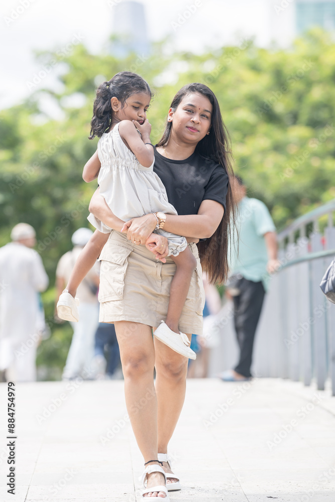 A 30-something Indian Malaysian mother wearing a miniskirt and her 5-year-old daughter in a white dress spending time joyfully on a bridge in City Centre, Kuala Lumpur, Malaysia. A 30-something Indian Malaysian mother wearing a miniskirt and her 5-year-old daughter in a white dress spending time joyfully on a bridge in City Centre, Kuala Lumpur, Malaysia.