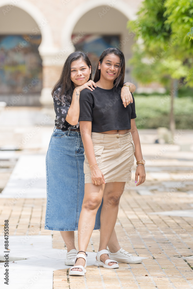 Two 30-something Indian Malaysian women posing in various ways and enjoying their holiday in front of a beautiful building in a historic cobblestone park in City Centre, Kuala Lumpur, Malaysia. Two 30-something Indian Malaysian women posing in various ways and enjoying their holiday in front of a beautiful building in a historic cobblestone park in City Centre, Kuala Lumpur, Malaysia.