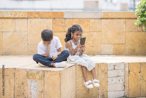 Photography A 30-something Indian Malaysian mother in a denim skirt and her 7-year-old son in a white T-shirt spending time joyfully in a historic cobblestone park in City Centre, Kuala Lumpur, Malaysia