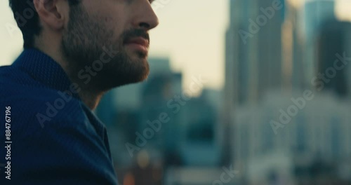 Young man standing on a bridge looking out at the sunset