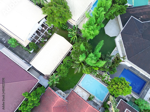 Aerial drone shot of several villas with swimming pools and lush gardens.  