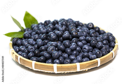 Close-up of stacked raw blueberry fruits with leaves on bamboo basket and white floor, South Korea 