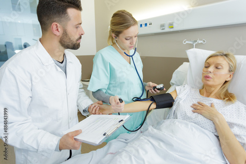 nurse measuring blood pressure of elderly woman indoors