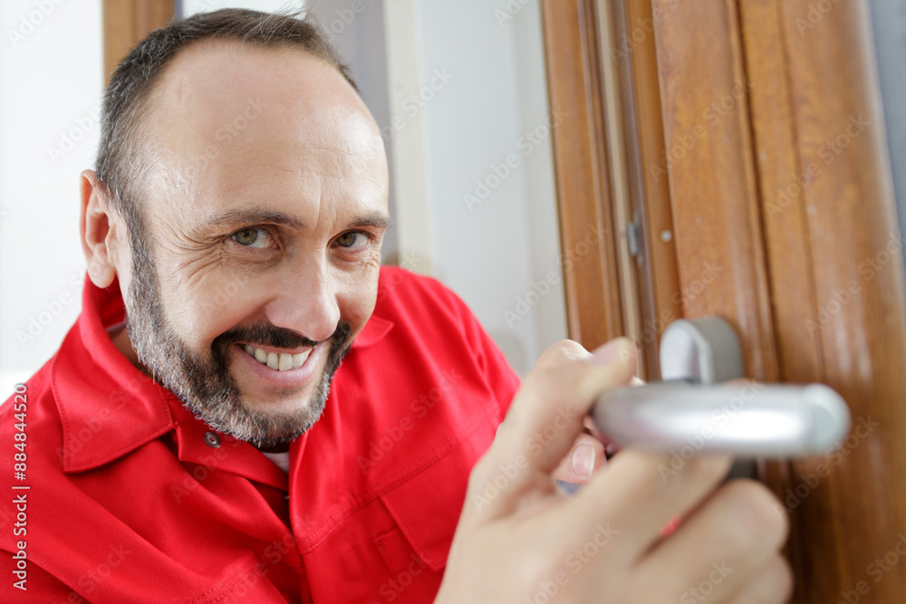 Φωτογραφία a happy male worker repairing the doorknob