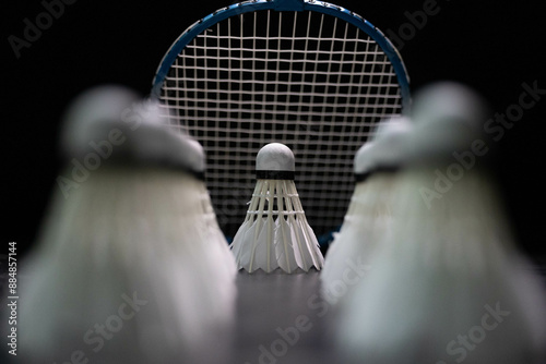  badminton shuttlecocks and badminton rackets are placed on a black background. photo