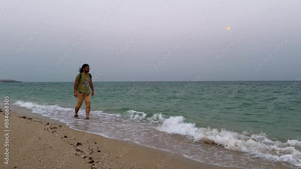 man is walking along the beach sea line wear olive green shirt and short in summer season early morning curly hair long hair male travel rural village countryside twilight iran nature landscape man is walking along the beach sea line wear olive green shirt and short in summer season early morning curly hair long hair male travel rural village countryside twilight iran nature landscape