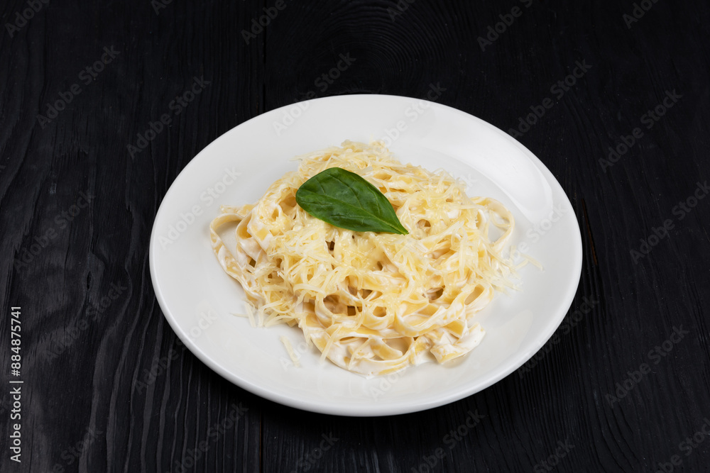 Pasta with sauce and basil in plate on black wooden background Pasta with sauce and basil in plate on black wooden background