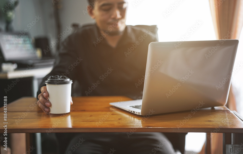The manager of an Asian man sipping coffee on his desk in a radiant manner.
The manager of an Asian man sipping coffee on his desk in a radiant manner.