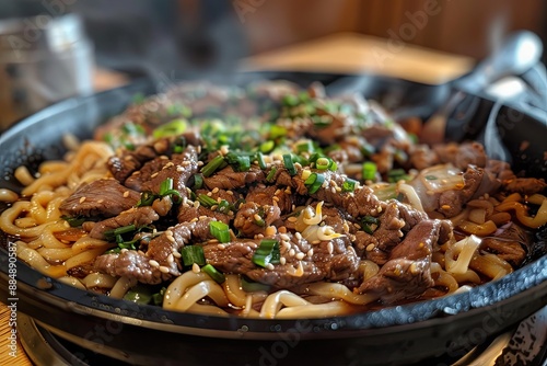 Savory sizzling beef and udon noodles in a hot black bowl photo