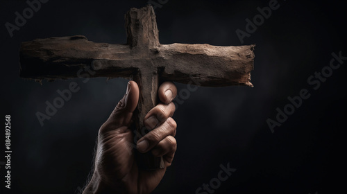 Hand Firmly Grasping a Rough Wooden Cross Against Dark Background 
