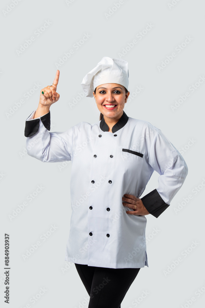 Happy Indian Female Chef or professional cook Pointing at blank - Isolated on White Happy Indian Female Chef or professional cook Pointing at blank - Isolated on White