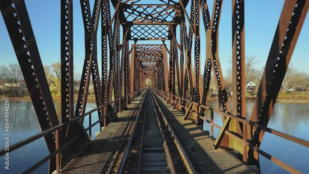 Drone flight on a rusty train bridge over a river with blue sky on a sunny day, dolly shot