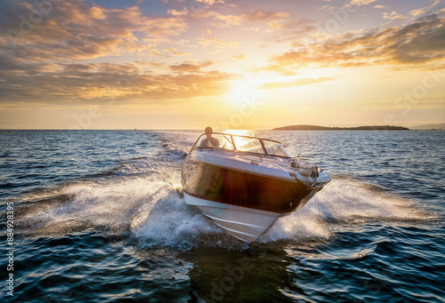 Aerial front view of a sports motor boat cruising with high speed over the blue sea during summer sunset time