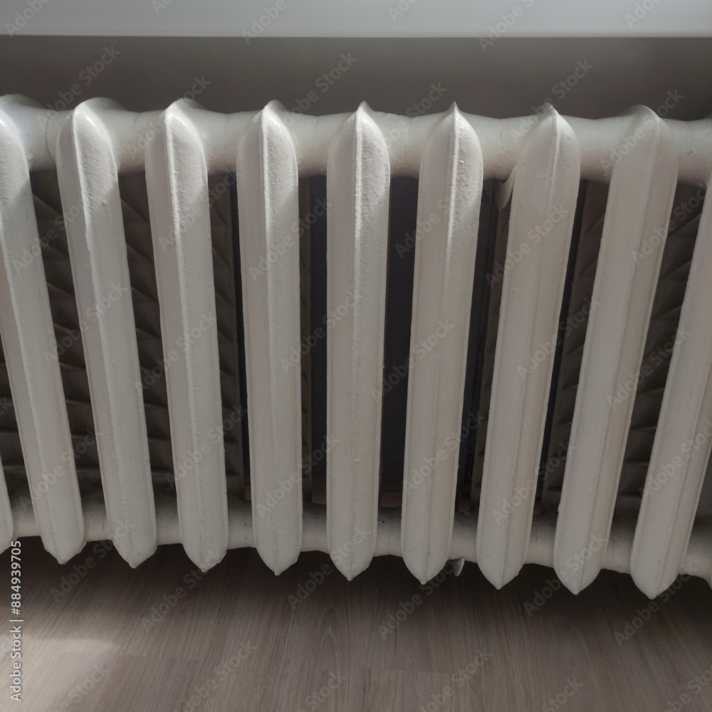 Old painted white iron radiator on a white wall