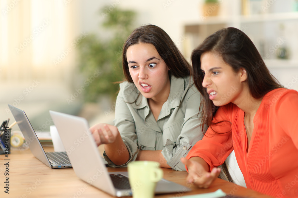 Two upset tele workers working checking laptop at home Two upset tele workers working checking laptop at home
