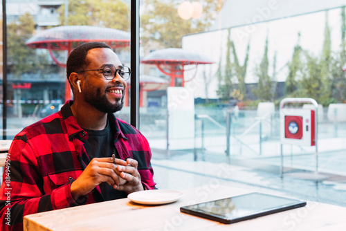 A man is drinking a cup of coffee while is looking out the window