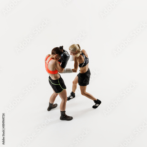 Female boxers in motion deliver powerful punches in an energetic match , training isolated on white background. Concept of combat sport, martial arts, strength, endurance