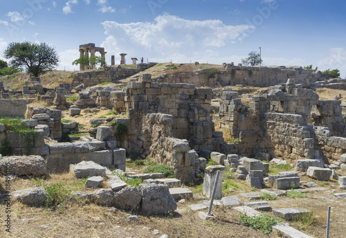 Corinth, Peloponnesus, Greece - August 10, 2023: Summer view of stone ruins and walls against pillars on the hill at Temple of Apollo
 photo