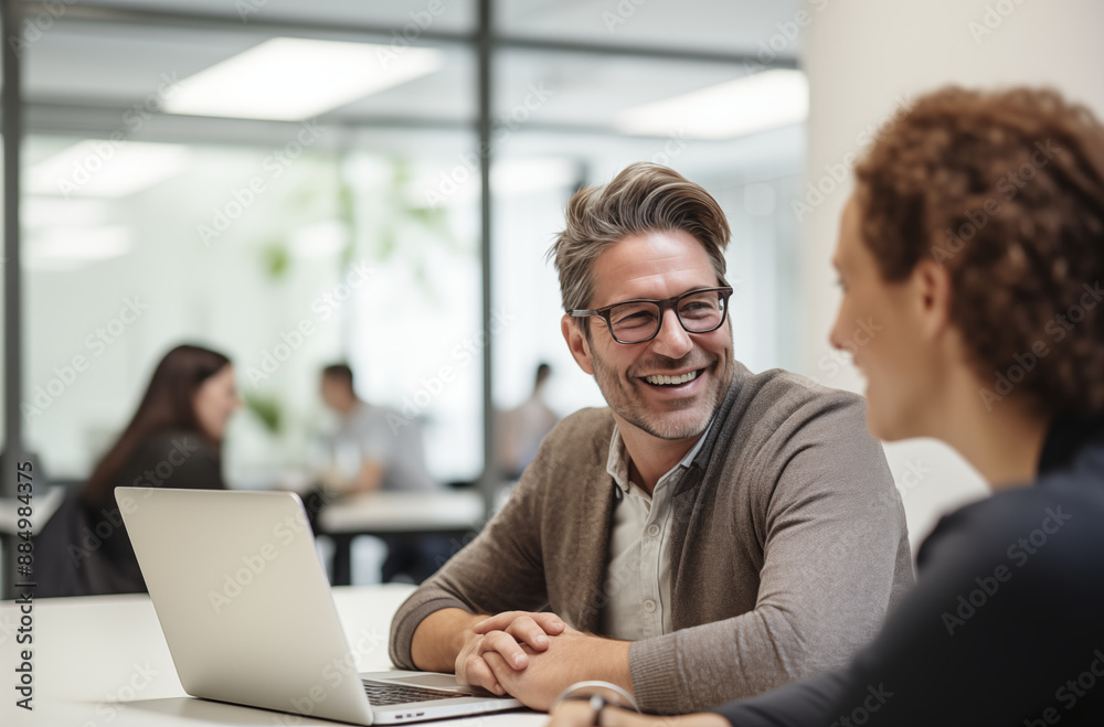 Smiling Businessman Engaging In Friendly Conversation With Colleague In Bright Office Space Smiling Businessman Engaging In Friendly Conversation With Colleague In Bright Office Space