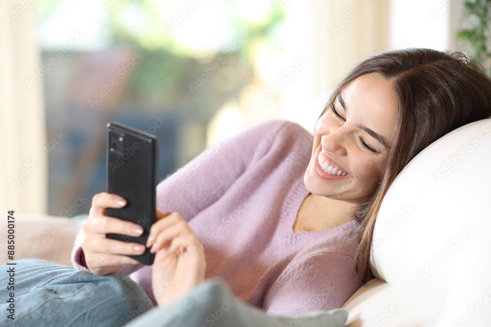 Happy woman in a couch checking smart phone Happy woman in a couch checking smart phone