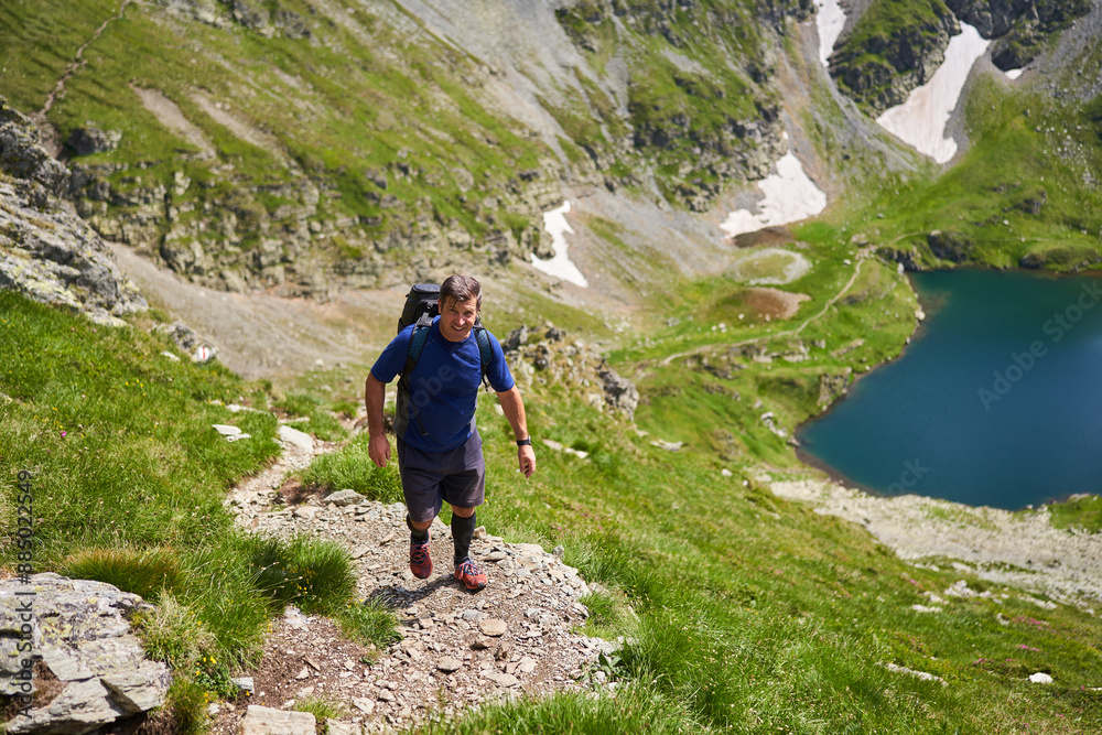 Man with backpack hiking on steep trail Man with backpack hiking on steep trail