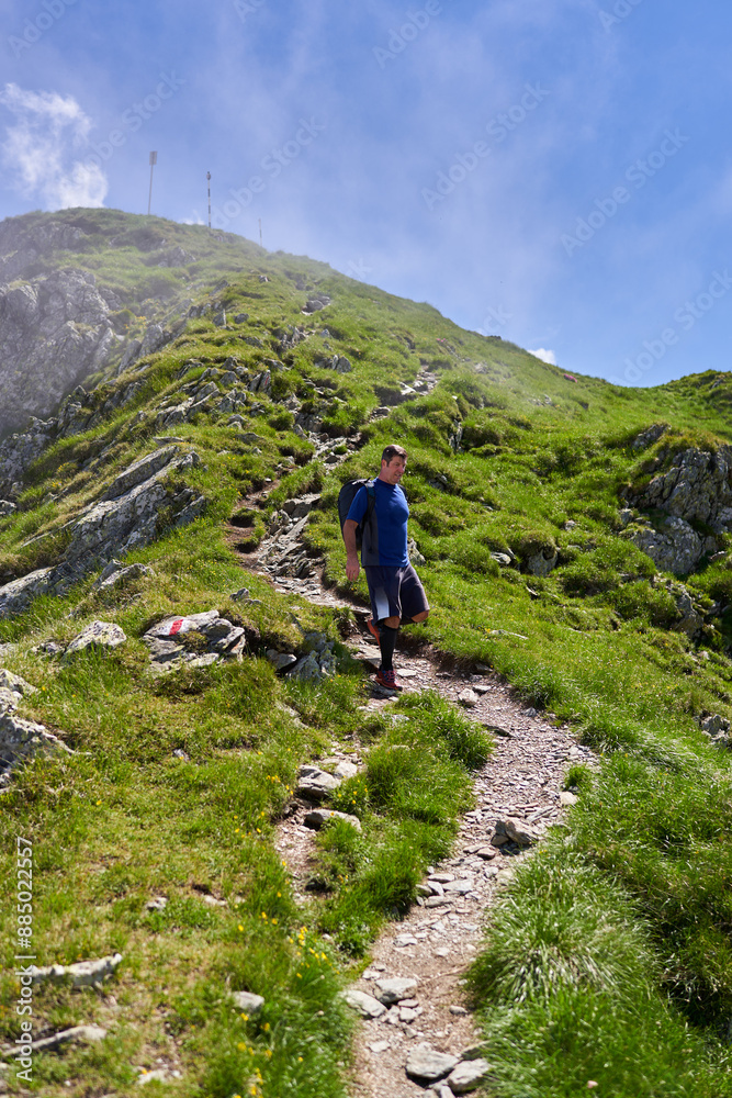 Exhausted hiker with backpack on a trail in the mountains