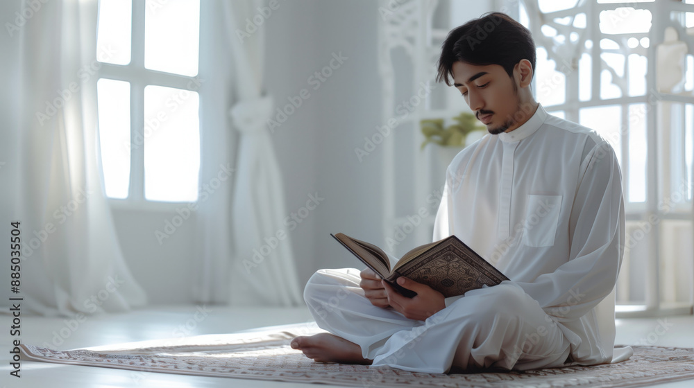Young man dressed in white traditional attire reading the Quran in a bright, serene room. Spiritual practice, meditation, religious devotion, peaceful living, Islamic culture, personal reflection. Young man dressed in white traditional attire reading the Quran in a bright, serene room. Spiritual practice, meditation, religious devotion, peaceful living, Islamic culture, personal reflection.