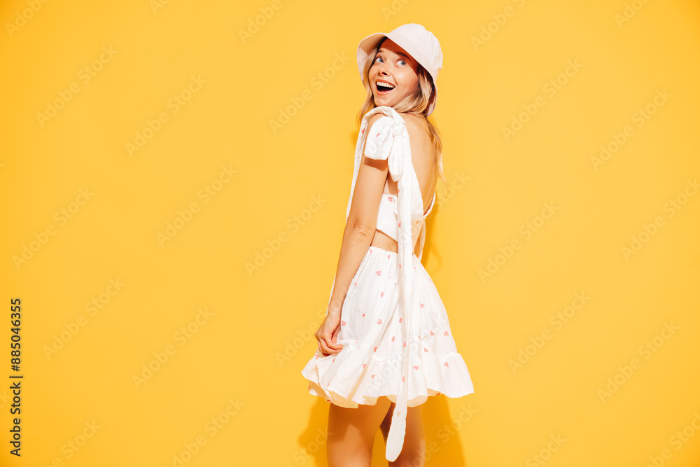 Young beautiful smiling blond female in trendy summer white dress clothes. Carefree woman posing near yellow wall in studio. Positive model in panama hat. Cheerful and happy, in panama Young beautiful smiling blond female in trendy summer white dress clothes. Carefree woman posing near yellow wall in studio. Positive model in panama hat. Cheerful and happy, in panama