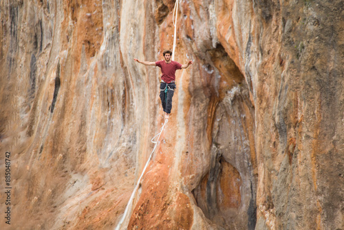 A man walks on a tightrope over an abyss.