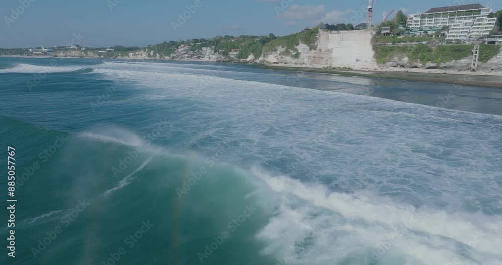 Low angle drone shot of surfers and blue waves with environmental destruction in background in Uluwatu Bali Indonesia Low angle drone shot of surfers and blue waves with environmental destruction in background in Uluwatu Bali Indonesia