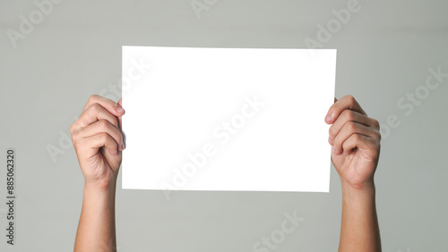 Close up of  men hands holding the white blank paper isolated on grey white background. Mockup for design 