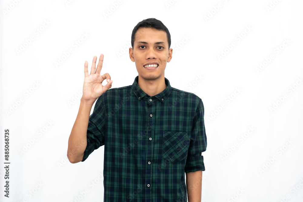 Asian man wearing a green checkered casual shirt stressed showing thumbs up that agree, okay, top. Isolated white background. Asian man wearing a green checkered casual shirt stressed showing thumbs up that agree, okay, top. Isolated white background.