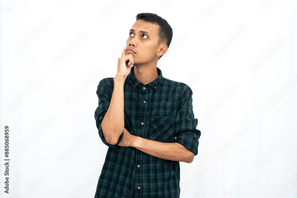 Asian man wearing a casual green checkered shirt poses thinking, looking for ideas. Isolated white background. Asian man wearing a casual green checkered shirt poses thinking, looking for ideas. Isolated white background.