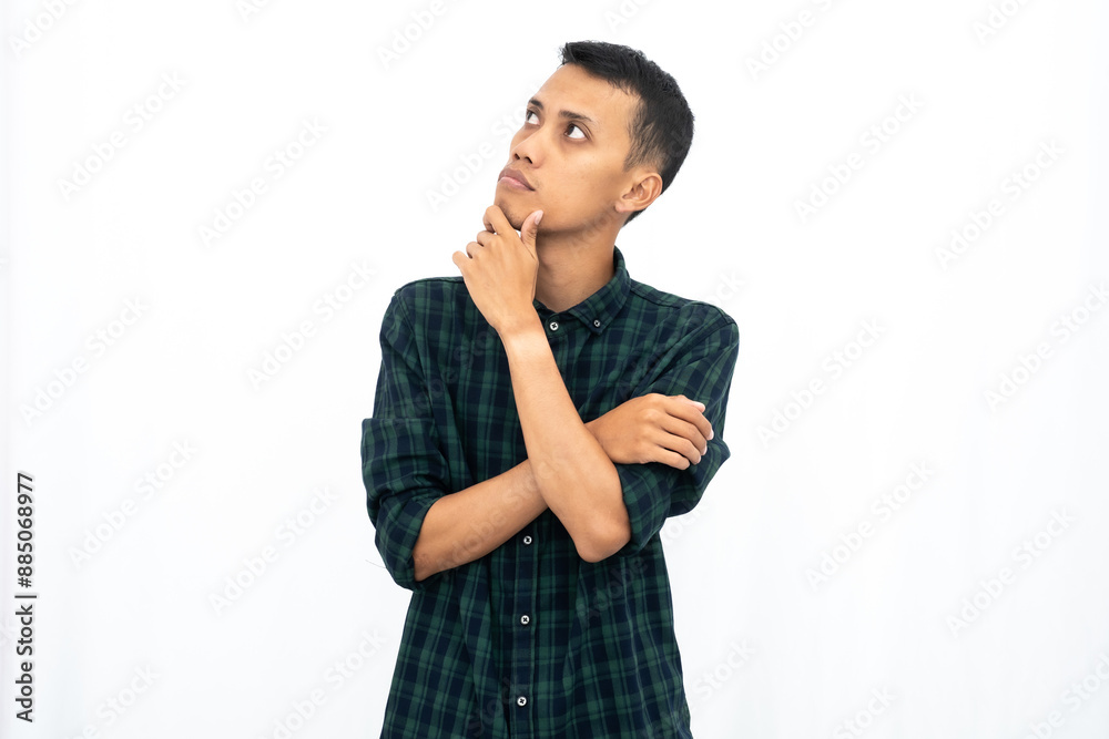 Asian man wearing a casual green checkered shirt poses thinking, looking for ideas. Isolated white background. Asian man wearing a casual green checkered shirt poses thinking, looking for ideas. Isolated white background.