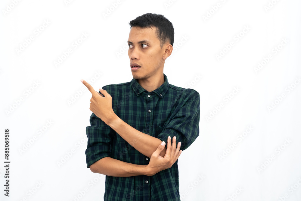 Asian man wearing green checkered casual shirt pointing to empty space for advertising. Isolated white background. Asian man wearing green checkered casual shirt pointing to empty space for advertising. Isolated white background.