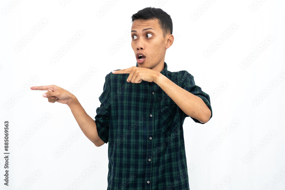 Asian man wearing green checkered casual shirt pointing to empty space for advertising. Isolated white background.