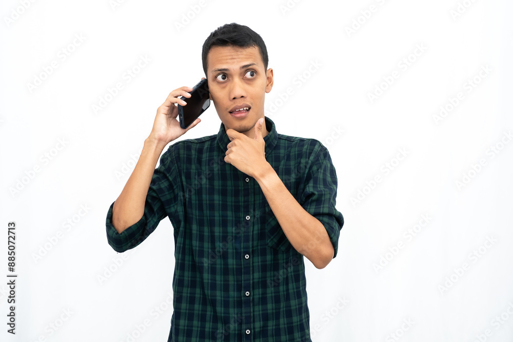 Asian man wearing a green checkered casual shirt is calling. Getting good news or surprises. Isolated white background. Asian man wearing a green checkered casual shirt is calling. Getting good news or surprises. Isolated white background.
