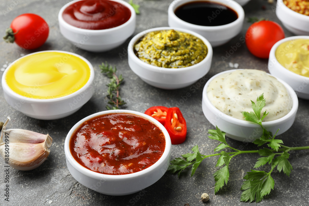 Many different sauces and spices on grey table, closeup Many different sauces and spices on grey table, closeup