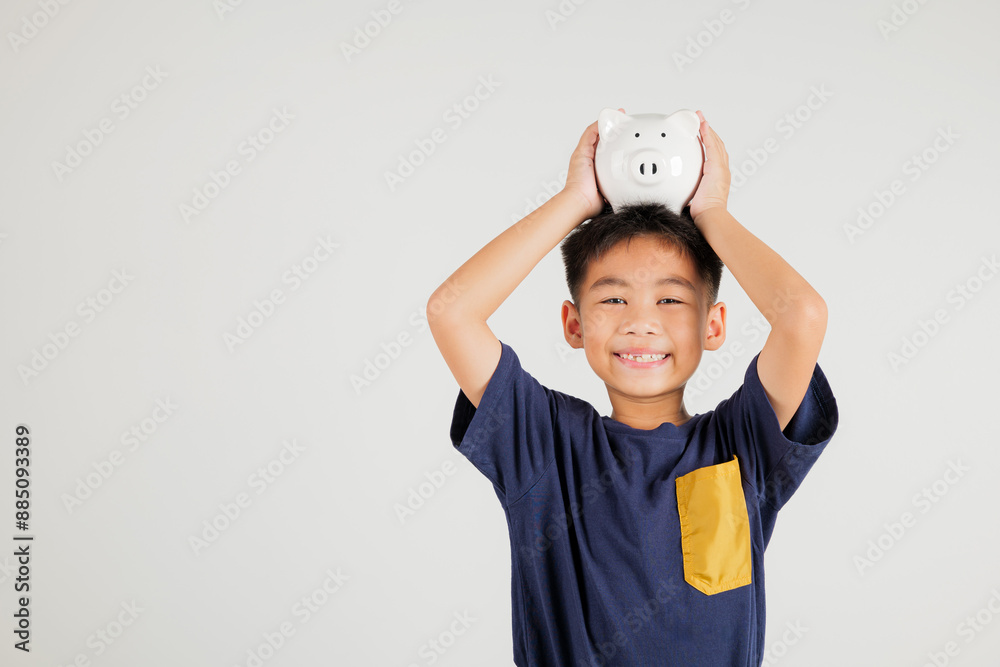 Asian little kid boy holding piggy bank bank over head in studio shot isolated on white background, Happy primary child lifestyle smiling with is white piggybank, Thai personal money savings Asian little kid boy holding piggy bank bank over head in studio shot isolated on white background, Happy primary child lifestyle smiling with is white piggybank, Thai personal money savings