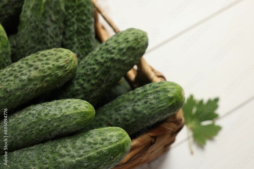 Fresh green cucumbers in wicker box on white table, closeup Fresh green cucumbers in wicker box on white table, closeup