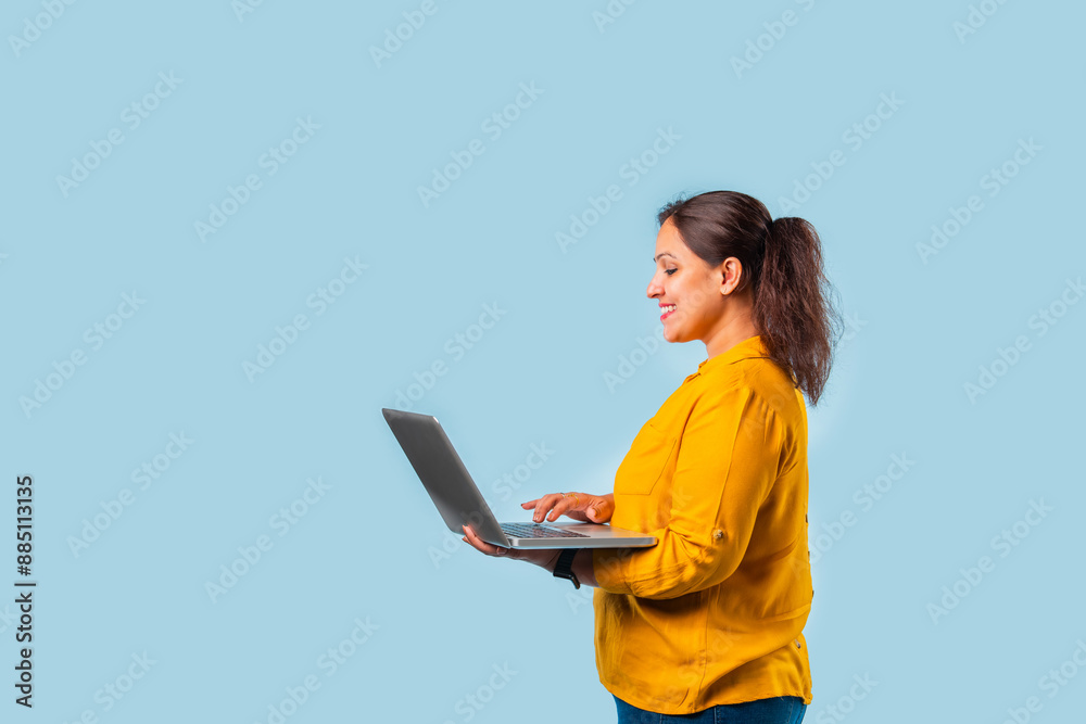 Indian Asian working woman using a laptop, light blue background Indian Asian working woman using a laptop, light blue background