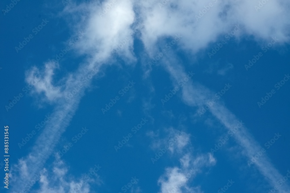 Beautiful clouds with contrails in the clear blue sky. Interesting contrails left by airplane in a shape of triangle. Beautiful clouds with contrails in the clear blue sky. Interesting contrails left by airplane in a shape of triangle.