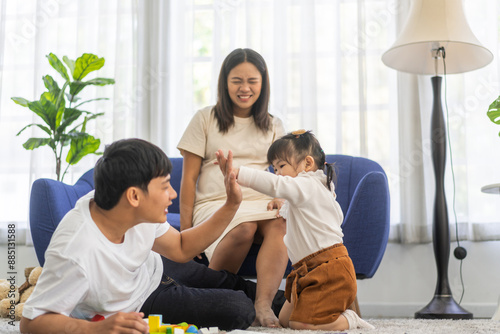 Portrait of enjoy happy love asian family father and mother with little asian girl smiling activity learn and skill brain play toy build wooden block board education game, children development at home