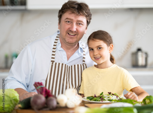 Father and daughter with cooked food in kitchen